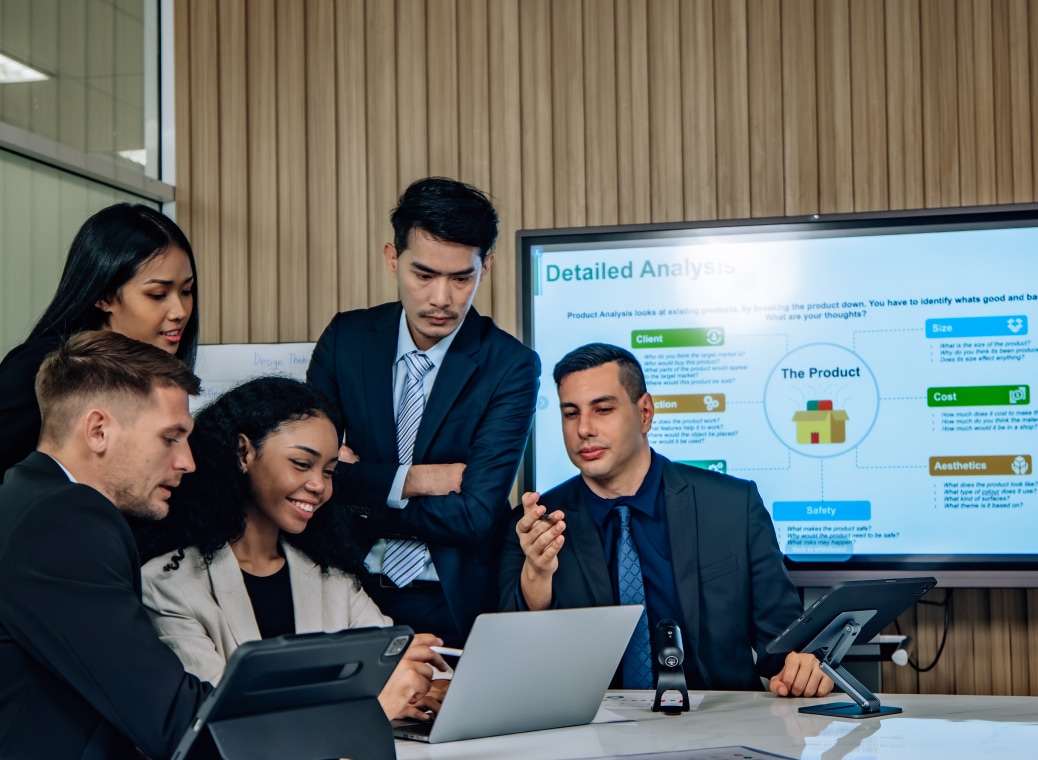 An employee presents work done on a laptop to his colleagues.