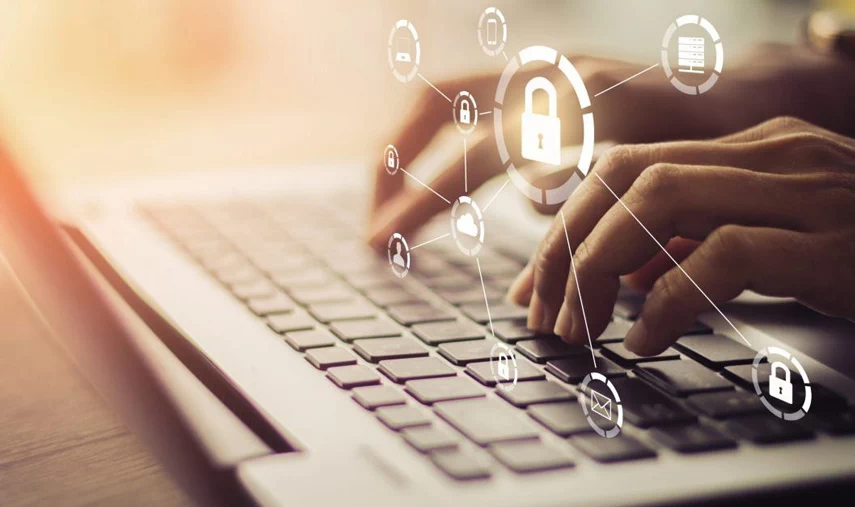 Hands on laptop with secure icons above.