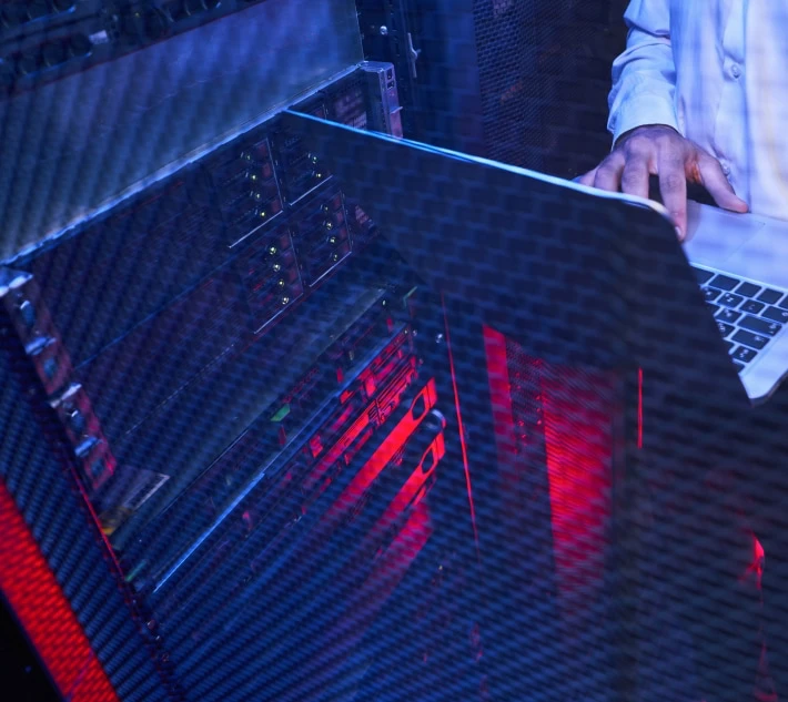 Some guy is working on a notebook in front of the server.